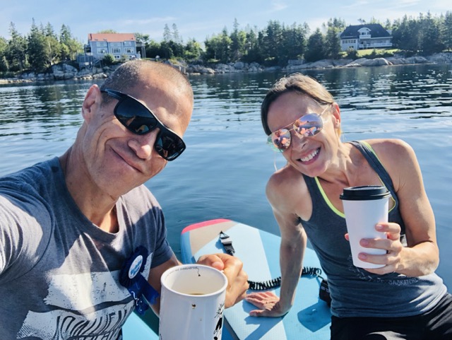 100X EDGE life coaches Phil and Catherine are having coffee in the middle of the ocean on a paddle board.