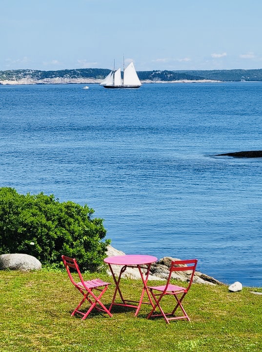 Red Roof retreat lawn with a red picnic table, St. Margarets Bay and the Bluenose sail boat in the background